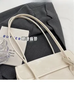 Close-up of cream underarm bag showing fine stitching and slim double shoulder straps