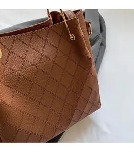 Detail shot of brown quilted leather texture and golden metal handle on the handbag