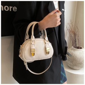 Close-up of a creamy white bowling bag with smooth PU leather and gold hardware
