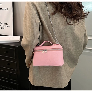 Pink lychee leather vanity case with silver chain strap shown worn by a model