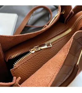 Close-up of golden zipper on brown lychee leather bucket bag with premium finish