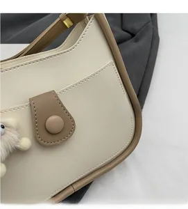 Detail of retro cream shoulder bag showing leather texture and plush charm accessory