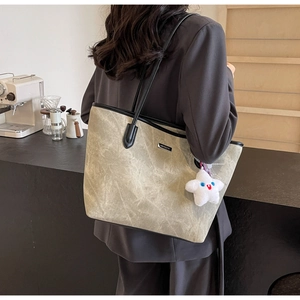 Close-up of grey textured tote bag featuring black trim and a white plush star charm