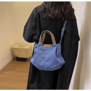Blue canvas tote bag with khaki handles shown on model back for size scale and fit