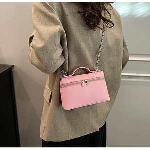 Detail of pink lychee pattern crossbody bag with golden chain strap and top handle