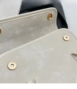 Detailed close-up of a silver magnetic snap closure and textured fabric on a cream handbag