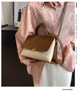 Detail of color-block leather handbag with gold buckle on pink shirt and white skirt