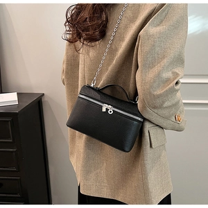 Close-up of black lychee grain leather crossbody bag with silver chain on a model