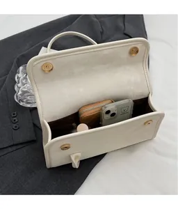 Interior detail of white shoulder bag showing magnetic gold buckles and spacious storage