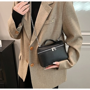 Close-up of black pebble leather crossbody box bag with silver chain and handle details
