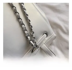 Close-up of white pearlescent drawstring backpack with silver chain and metal hardware