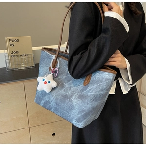Blue denim tote bag with brown leather trim and white star pendant detail