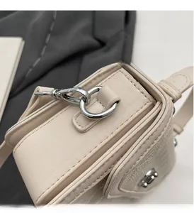 Detailed close-up of polished silver hardware and cream leather on the shoulder bag