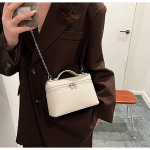 Detail of off-white lychee pattern leather handbag with silver chain and dual zippers