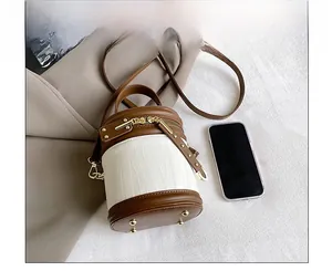 Detailed view of the cylindrical bucket bag showing metal feet and textured leather finish