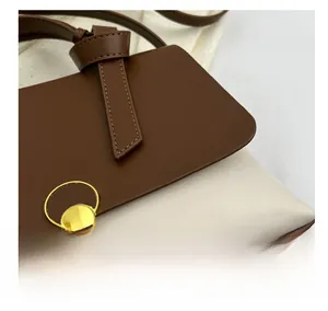 Detail of the brown and beige leather bag with a gold circular clasp and fine texture