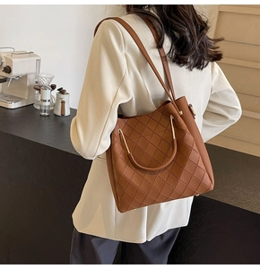 Close-up detail of a brown quilted tote bag with golden metal rings and leather texture