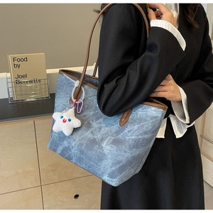Detailed side view of blue marble pattern tote bag with brown leather trim and star charm