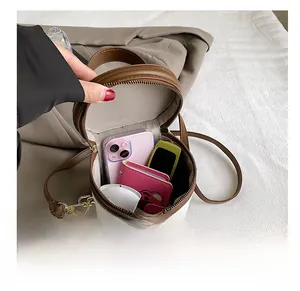 Top view of cylindrical crossbody bag interior holding a smartphone and wallet