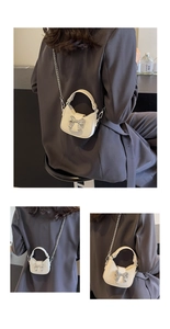 Close-up of cream mini half-moon bag featuring a silver metal bow and fine chain strap
