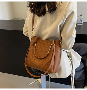 Detail of brown quilted bucket bag with gold handle and high-quality leather texture