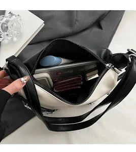 Vue intérieure d'un sac à bandoulière contrasté montrant un rangement spacieux