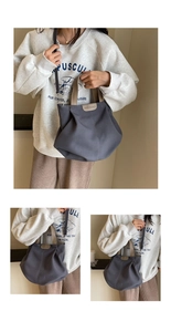 Detail of dark grey canvas tote bag with brown leather handles and adjustable strap