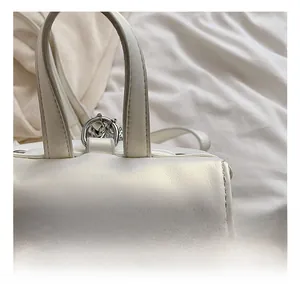 Close-up of white leather backpack handle with metallic hardware and textured flap detail