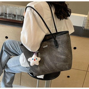 Detail of grey vintage textured leather tote bag with white plush star pendant charm
