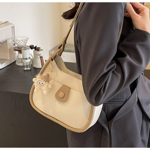 Close-up of hobo bag in cream and brown leather with cute plush monster charm
