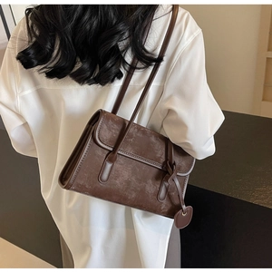 Detail of vintage dark brown tote bag with matte texture and decorative round pendant