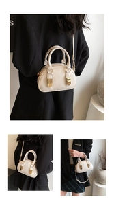 Detail view of cream bowling bag with gold buckles and detachable shoulder strap