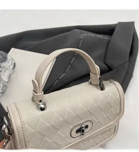 Detail of off-white crossbody bag with lychee grain texture and silver swivel lock
