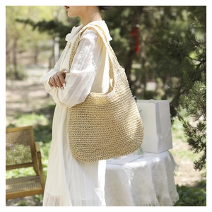 Gros plan sur un sac cabas beige en paille tressée avec motifs ajourés pour les vacances