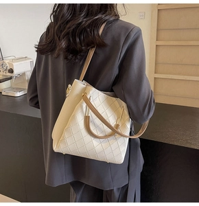 Close-up of beige quilted bucket bag with brown handles and gold hardware details