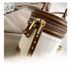 Detail of cylindrical bucket bag featuring brown leather and herringbone fabric stitching
