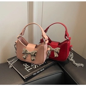 Close-up of crescent moon bags with large silver bow buckles and metal chain straps