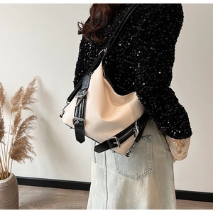 Détail du sac hobo en cuir brillant beige avec boucles noires et large bandoulière