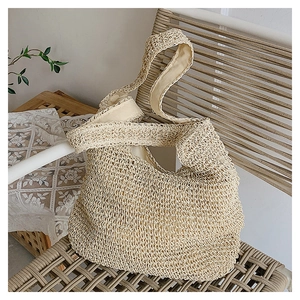 Gros plan détaillé sur la texture du sac en paille tissé et sa bandoulière large