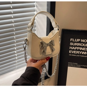 Detail of white PU leather handbag featuring silver bow buckle and metal chain strap