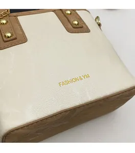 Gros plan détaillé du sac à main en cuir beige texturé marbre avec logo métallique doré