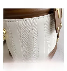 Detailed macro view of white wave-textured bucket bag with brown leather trim and gold rivets