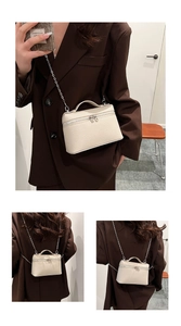 Detail of beige lychee textured mini vanity bag with silver chain strap on a model