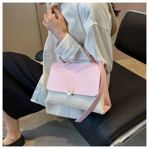 Detail of a pink and cream contrast crossbody bag with golden metal buckle on a model