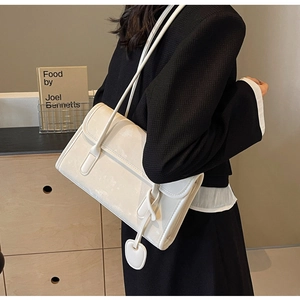 Detailed shot of white leather rectangular shoulder bag with heart pendant on model