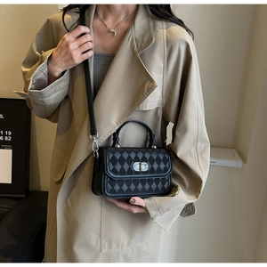 Detail showing the black quilted argyle texture and silver metal twist lock on the handbag