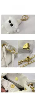 Dettaglio borsa tote bianca con trama litchi, catena dorata e ciondolo di peluche