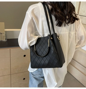 Chic black quilted bucket bag with diamond lattice pattern worn on shoulder in minimalist setting