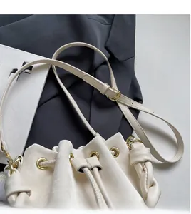 Detail of cream drawstring bucket bag with woven side texture and adjustable strap