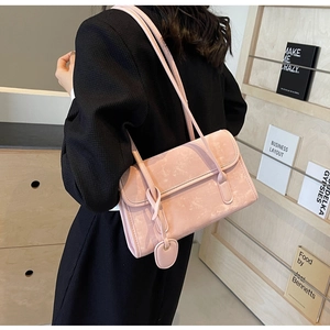 Detail of light pink shoulder bag with heart pendant and textured matte finish on leather